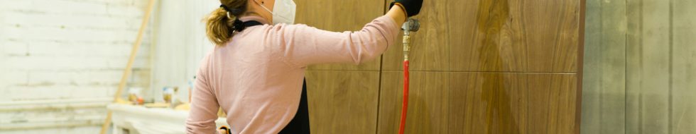 Girl applying a spray finish to an external wooden door