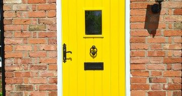 An external wooden door painted a bright and vibrant yellow