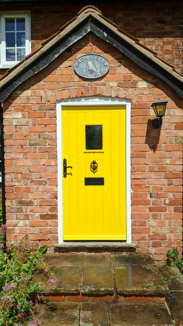 An external wooden door painted a bright and vibrant yellow