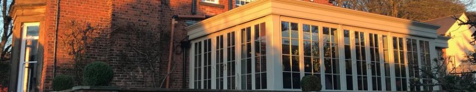 Wooden conservatory attached to a sizeable home.