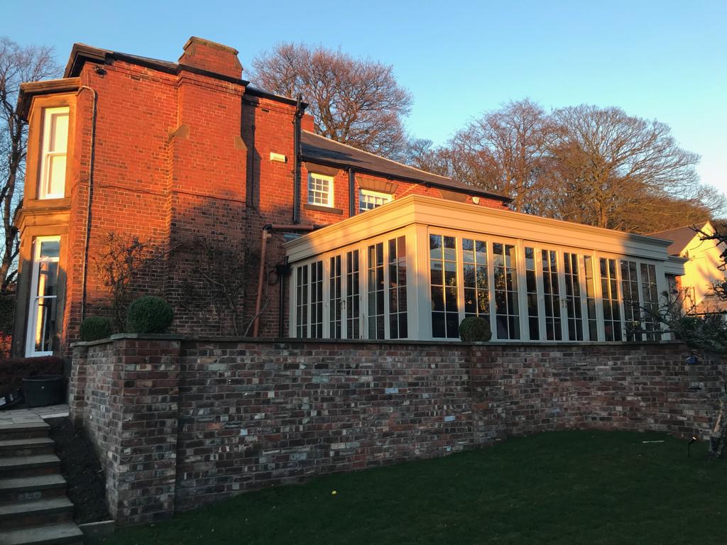 Wooden conservatory attached to a sizeable home.