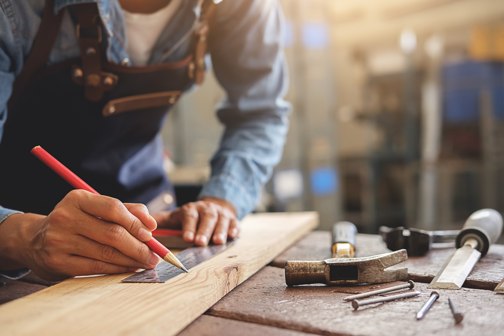 A joiner using a ruler to decide where he will cut wood